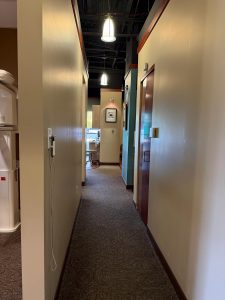 Carpeted hallway with a view of treatment rooms